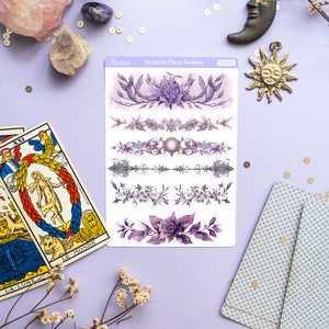 Peut inclure: Une feuille d'autocollants de s&eacute;parateurs floraux victoriens avec des motifs floraux violets et gris. Les autocollants sont sur un fond violet clair avec un cristal rose, une bougie blanche et une lune argent&eacute;e.