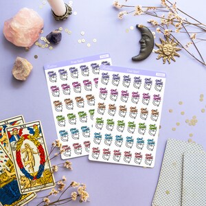 May include: Two sheets of stickers with colorful "Prep Spell" and "Cast Spell" text in a circle design. The stickers are on a purple background with tarot cards, crystals, and other witchy decor.