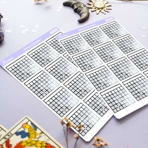 Op de afbeelding: Twee vellen met galaxy-kalender stickers met een rasterpatroon en een grijs verloop. De stickers zijn gelabeld met "Galaxy Calendars" en "Astro" met het jaar "2023" gedrukt op elk vel.