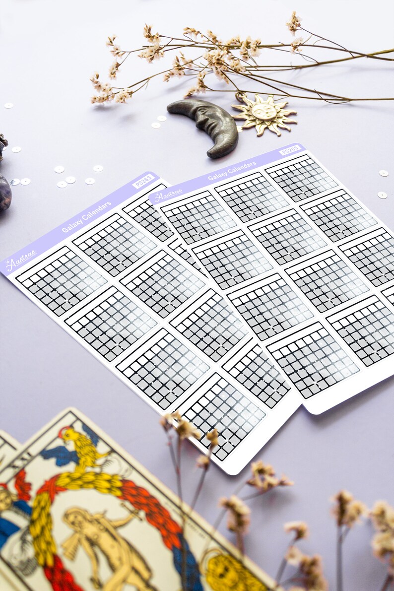 Op de afbeelding: Twee vellen met galaxy-kalender stickers met een rasterpatroon en een grijs verloop. De stickers zijn gelabeld met "Galaxy Calendars" en "Astro" met het jaar "2023" gedrukt op elk vel.