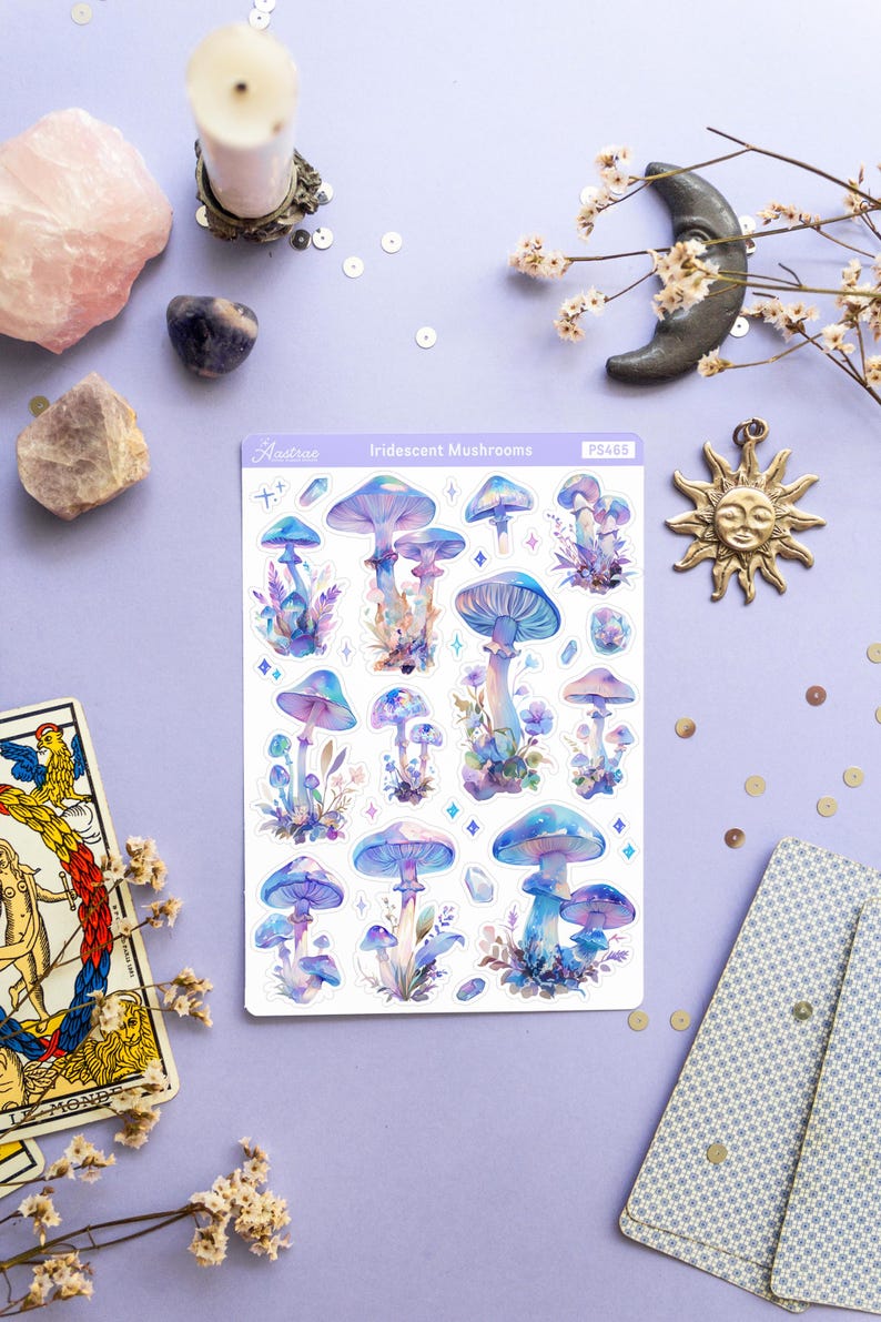 Puede incluir: Una hoja de pegatinas de setas iridiscentes con fondo blanco. Las pegatinas presentan varias setas azules y moradas con puntos blancos y detalles de purpurina. La hoja est&aacute; etiquetada como "Iridescent Mushrooms" y "PS465".