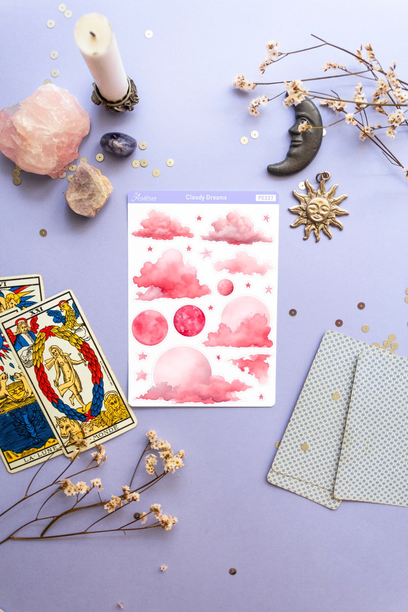 May include: A sheet of pink and white stickers with a cloudy dreams theme. The stickers feature pink clouds, stars, and moons. The sheet is labeled "Cloudy Dreams" and has a product number.
