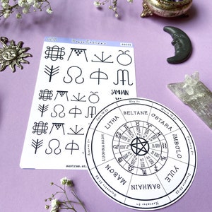 May include: A set of two stickers featuring a wheel of the year with the eight pagan holidays and a sheet of symbols representing each holiday. The wheel of the year includes the names of the holidays: Yule, Samhain, Mabon, Lughnasadh, Litha, Beltane, Ostara, and Imbolg. The symbols include a tree, a crescent moon, a circle with a dot in the center, a circle with a cross in the center, a circle with a spiral, a circle with a triangle, a circle with a square, and a circle with a star.
