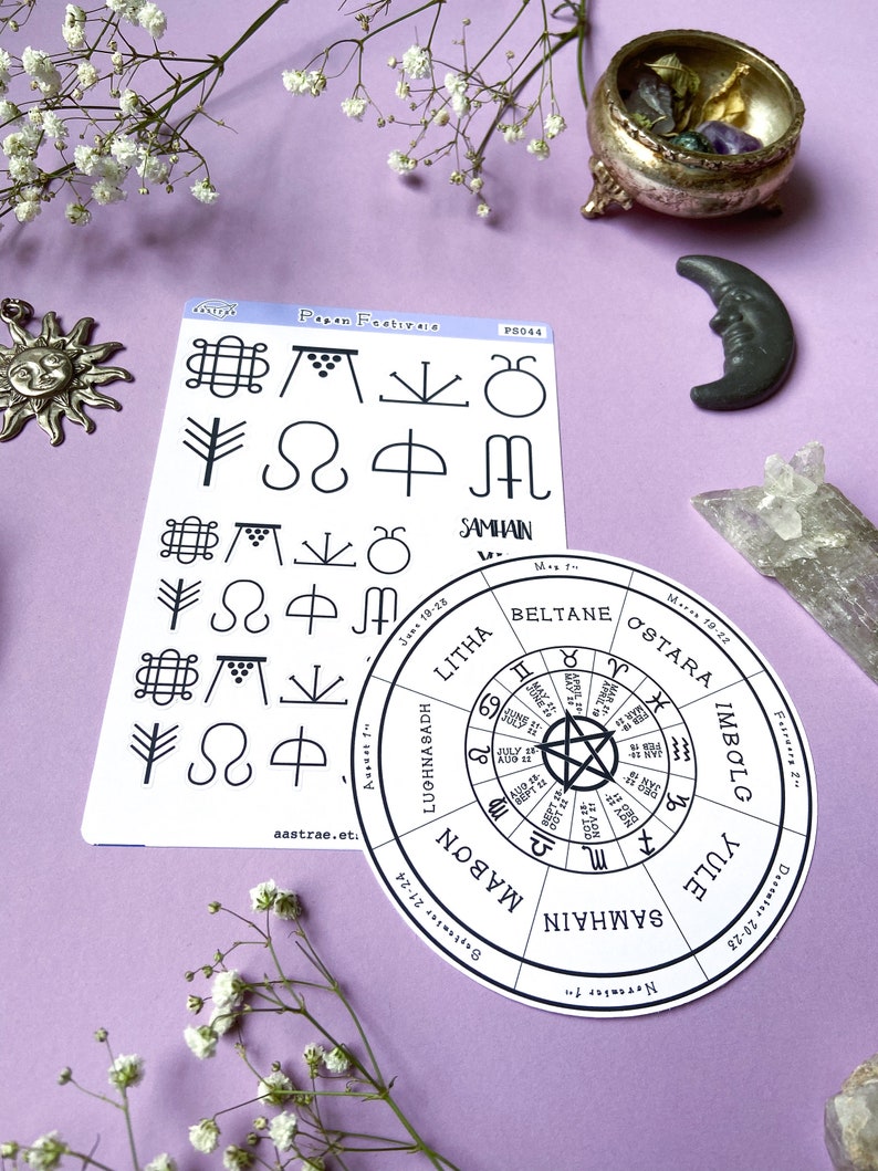 May include: A set of two stickers featuring a wheel of the year with the eight pagan holidays and a sheet of symbols representing each holiday. The wheel of the year includes the names of the holidays: Yule, Samhain, Mabon, Lughnasadh, Litha, Beltane, Ostara, and Imbolg. The symbols include a tree, a crescent moon, a circle with a dot in the center, a circle with a cross in the center, a circle with a spiral, a circle with a triangle, a circle with a square, and a circle with a star.
