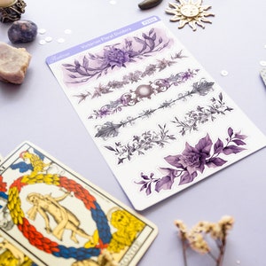 Peut inclure: Une feuille d'autocollants de s&eacute;parateurs floraux violets et gris avec le texte "Victorian Floral Dividers" et "Astrozee" sur la feuille. Les autocollants sont sur une surface violet clair avec une carte de tarot et des fleurs s&eacute;ch&eacute;es.