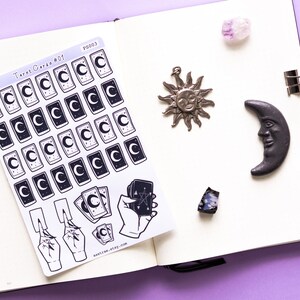 May include: A sheet of stickers featuring tarot card designs with a crescent moon and stars. The stickers are on a white background and are arranged in a grid pattern. The sheet also includes stickers of hands holding tarot cards. The text "Tarot Cards #01" and "PS003" is visible on the sheet.