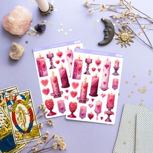 Pode incluir: Duas folhas de adesivos com velas de feiti&ccedil;o de amor rosa e roxas com cora&ccedil;&otilde;es e casti&ccedil;ais. Os adesivos est&atilde;o sobre um fundo roxo com cartas de tar&ocirc;, cristais e flores.