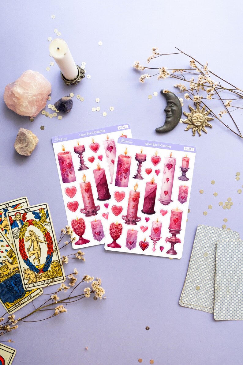 Pode incluir: Duas folhas de adesivos com velas de feiti&ccedil;o de amor rosa e roxas com cora&ccedil;&otilde;es e casti&ccedil;ais. Os adesivos est&atilde;o sobre um fundo roxo com cartas de tar&ocirc;, cristais e flores.