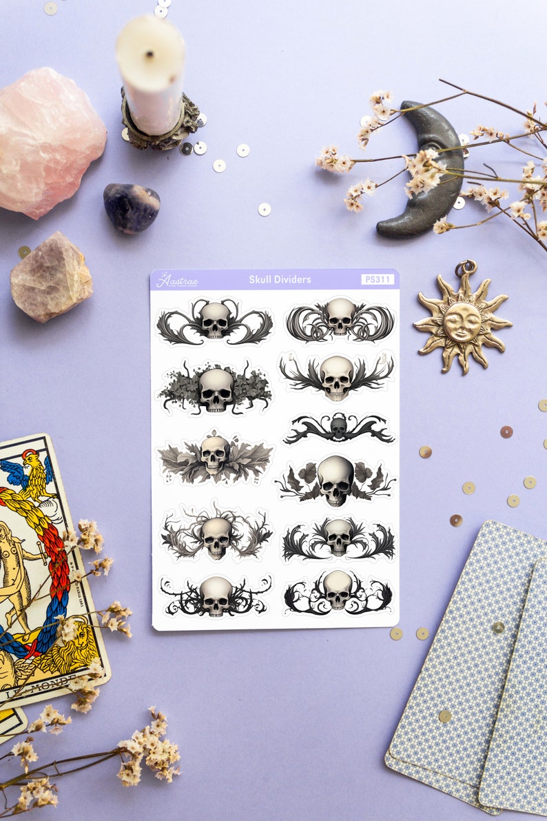 May include: A sheet of skull divider stickers with a white background. The stickers feature black and white illustrations of skulls with intricate floral designs. The sheet is labeled "Skull Dividers" and "PS311".