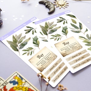 May include: A sheet of stickers featuring illustrations of bay leaves and text about the herb's properties. The text reads "Bay, Protection, Purification, Psychic Powers, Strength, Healing, Element: Fire, Planet: Sun, Deities: Aesculapius, Apollo".