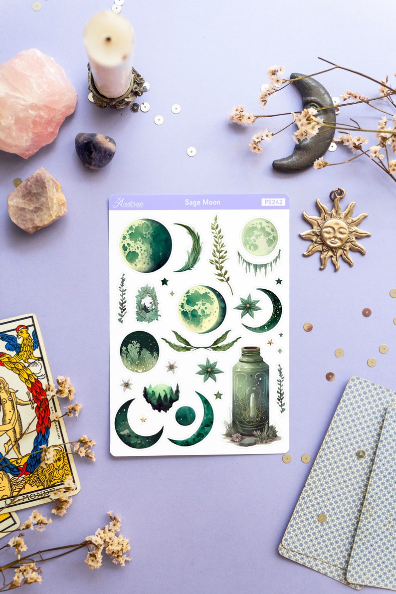 Puede incluir: Una hoja de pegatinas con un esquema de color verde y blanco con varias fases lunares, estrellas e ilustraciones bot&aacute;nicas. La hoja de pegatinas est&aacute; etiquetada como "Sage Moon" y "PS242".