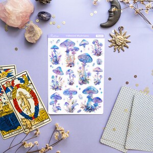 Puede incluir: Una hoja de pegatinas de setas iridiscentes con fondo blanco. Las pegatinas presentan varias setas azules y moradas con puntos blancos y un acabado brillante. La hoja est&aacute; etiquetada como "Iridescent Mushrooms" y "PS463".