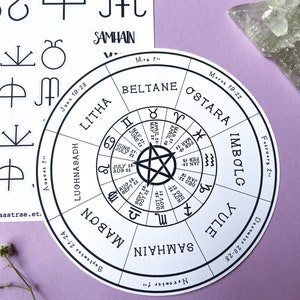 May include: A white circle with black text and a pentagram in the center. The text includes the names of the eight pagan holidays: Samhain, Mabon, Lughnasadh, Litha, Beltane, Ostara, Imbolc, and Yule. The dates of each holiday are listed around the circle.