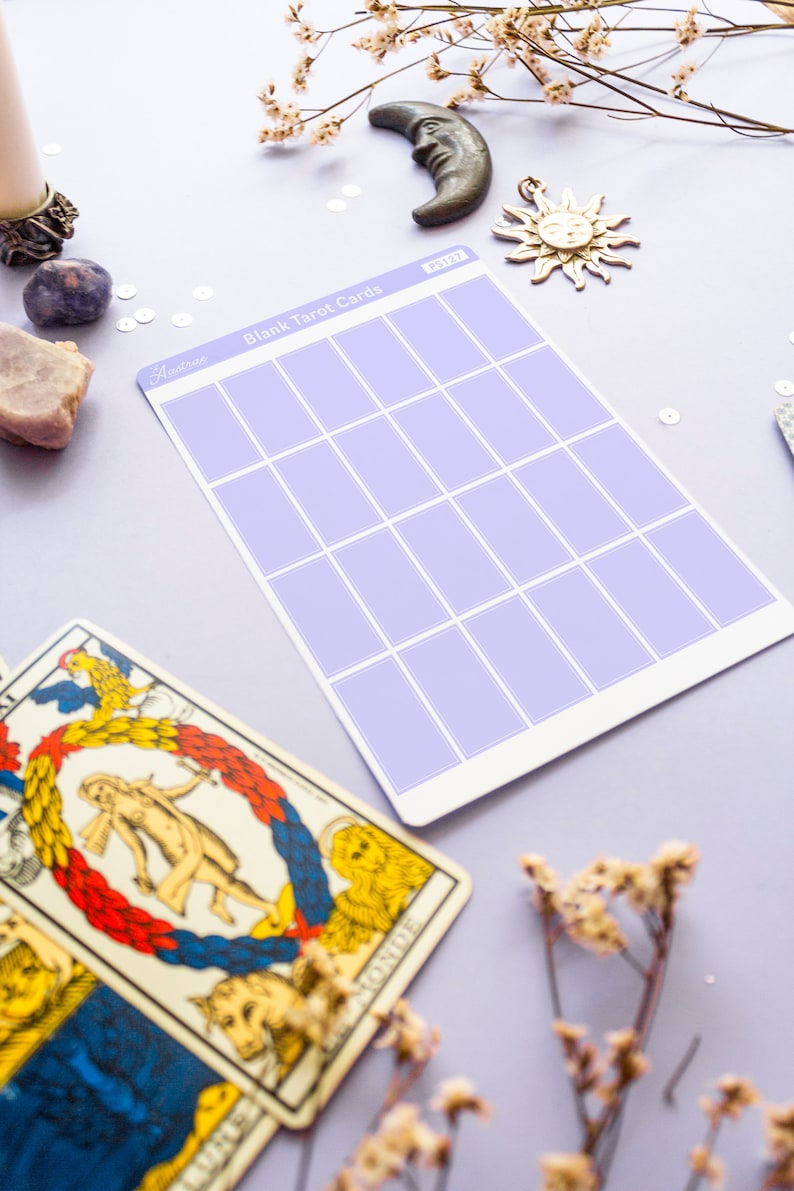 May include: A sheet of blank tarot cards with a lavender grid pattern, labeled "Blank Tarot Cards". The image includes a vintage tarot card, a crescent moon, a sun charm, and dried flowers, all on a lavender surface.