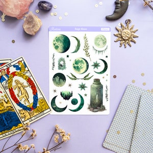 Puede incluir: Una hoja de pegatinas con tem&aacute;tica de luna de salvia con ilustraciones de lunas, estrellas, hojas y una botella. La hoja de pegatinas es blanca con un borde morado y el texto "Sage Moon" en negro.
