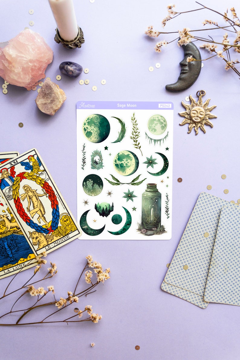 Puede incluir: Una hoja de pegatinas con tem&aacute;tica de luna de salvia con ilustraciones de lunas, estrellas, hojas y una botella. La hoja de pegatinas es blanca con un borde morado y el texto "Sage Moon" en negro.