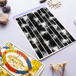 May include: A sheet of washi tape with a black and white night sky design. The tape is divided into 10 vertical strips, each with a different section of the night sky. The text "Night Sky Washi" is printed on the sheet.