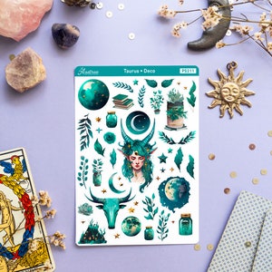 May include: A sheet of stickers featuring a green and gold Taurus zodiac sign, a woman with green hair and horns, a crescent moon, stars, and plants. The sticker sheet is labelled "Taurus Deco" and "PS211".