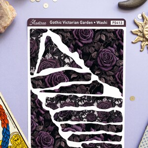 May include: A sheet of washi tape with a gothic Victorian garden design. The tape features a dark background with purple roses and leaves. The tape is cut into different shapes, including a large triangle and several rectangles. The text "Gothic Victorian Garden - Washi" and "PS413" is printed on the tape.