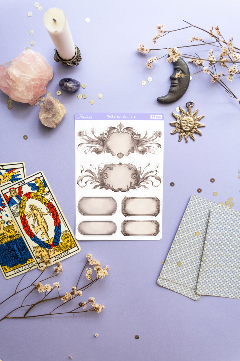 K&ouml;nnte beinhalten: Ein Bogen mit viktorianischen Banner-Aufklebern mit verzierten Rahmen und leeren Feldern zum Beschreiben. Die Aufkleber befinden sich auf einem violetten Hintergrund mit Tarotkarten, Kristallen und anderen Dekoartikeln.