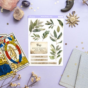 May include: A sheet of stickers featuring illustrations of bay leaves and text about the herb's properties. The text reads "Witch Herbs - Bay", "Bay", "Protection - Purification - Psychic Powers - Strength - Healing", "element: fire", "planet: sun", and "deities: Aesculapius, Apollo, Ceres, Faunus, Eros".