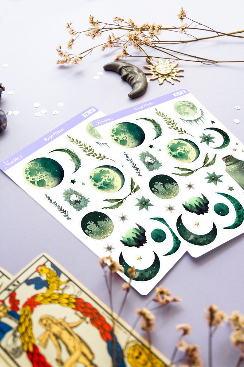 Puede incluir: Una hoja de pegatinas con fases lunares verdes y blancas, estrellas e ilustraciones bot&aacute;nicas. Las pegatinas est&aacute;n etiquetadas como "Sage Moon" y "Austera".
