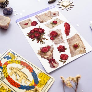May include: A sheet of stickers featuring Victorian-era love letters, roses, and a feather. The stickers are on a white background with a light purple border. The text "Victorian Love Letters" is printed on the sheet.