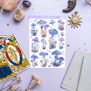 Puede incluir: Una hoja de pegatinas de setas iridiscentes con fondo blanco. Las pegatinas presentan varias setas azules y moradas con manchas blancas y un fondo blanco. La hoja est&aacute; etiquetada como "Iridescent Mushrooms" y "PS463".