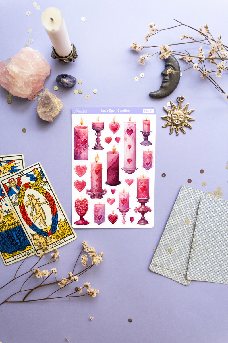 Pode incluir: Uma folha de adesivos com ilustra&ccedil;&otilde;es de velas rosa e roxas com detalhes dourados. Os adesivos s&atilde;o etiquetados como "Love Spell Candles" e "Aestree PS321".