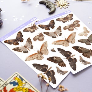 May include: Two sheets of stickers featuring vintage moth illustrations. The stickers are white with brown and beige moths. The text on the stickers reads "Vintage Moths" and "Aestrea".