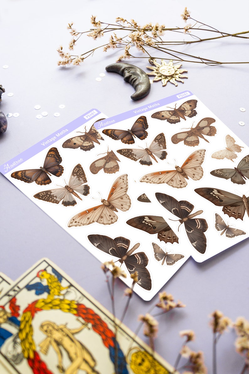 May include: Two sheets of stickers featuring vintage moth illustrations. The stickers are white with brown and beige moths. The text on the stickers reads "Vintage Moths" and "Aestrea".