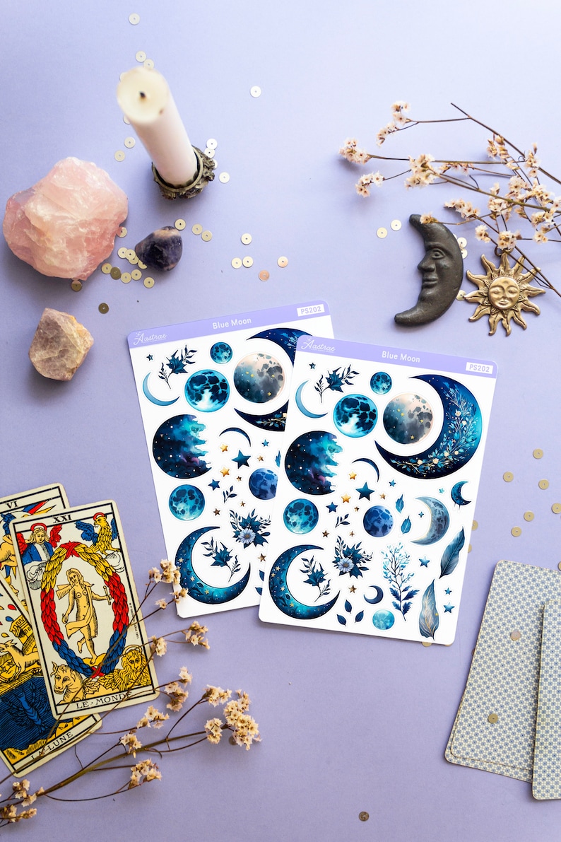 May include: Two sheets of blue moon themed stickers with a variety of blue moons, stars, and floral designs. The stickers are on a purple background with a candle, crystals, and tarot cards.