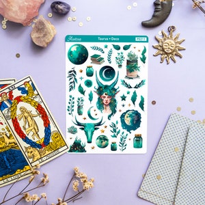 May include: A sheet of stickers featuring a green and gold design with a variety of images, including a woman with green hair, a bull, a crescent moon, stars, and jars. The sheet is labelled "Astrae Taurus Deco PS211".