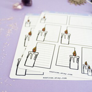 May include: A set of printable planner stickers featuring a candle with a flame. The stickers are white with black outlines and have a lined area for writing. The stickers are on a purple background with glitter.
