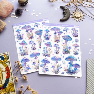 Puede incluir: Dos hojas de pegatinas de setas iridiscentes con fondo blanco. Las pegatinas presentan ilustraciones de acuarela de setas en tonos azules, morados y rosas. El texto "Iridescent Mushrooms" est&aacute; impreso en cada hoja.
