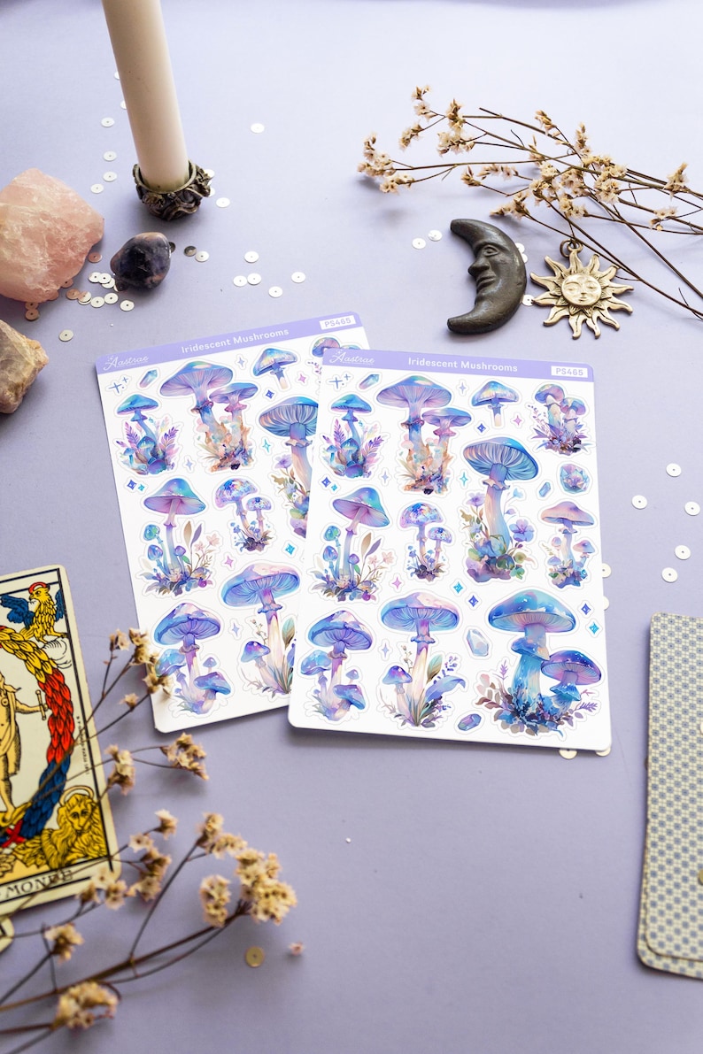 Puede incluir: Dos hojas de pegatinas de setas iridiscentes con fondo blanco. Las pegatinas presentan ilustraciones de acuarela de setas en tonos azules, morados y rosas. El texto "Iridescent Mushrooms" est&aacute; impreso en cada hoja.