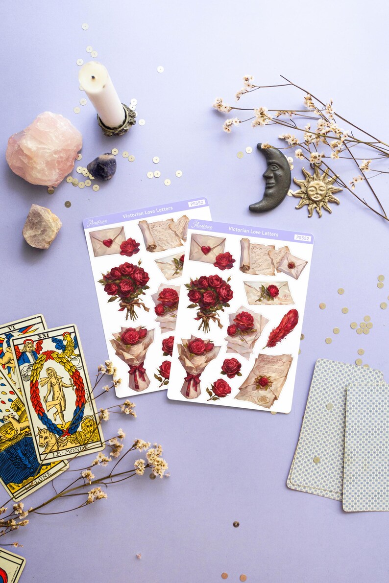 May include: Two sheets of stickers featuring Victorian-era love letters, roses, and envelopes. The stickers are on a light purple background with gold glitter, a pink crystal, a white candle, a silver candlestick, a white flower sprig, a black crescent moon, and a gold sun.