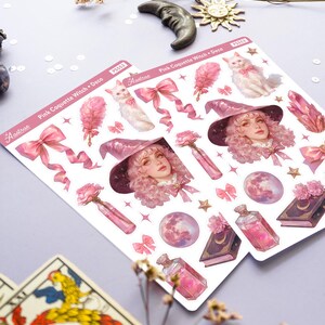May include: A sheet of pink and white stickers featuring a witch with pink hair and a pink hat, a white cat, pink bows, a pink moon, a pink potion bottle, and a pink book with a crescent moon on the cover. The stickers are labeled "Pink Coquette Witch + Deco" and "Astrae".