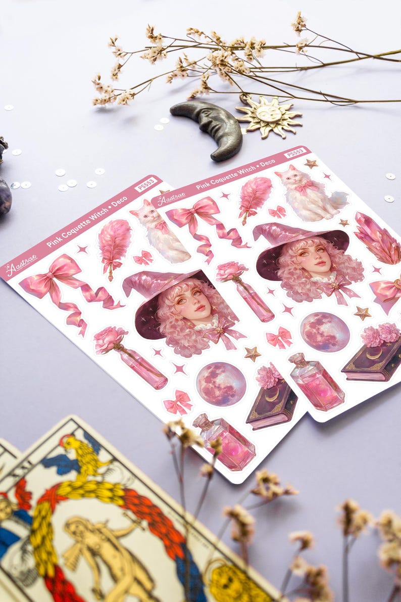 May include: A sheet of pink and white stickers featuring a witch with pink hair and a pink hat, a white cat, pink bows, a pink moon, a pink potion bottle, and a pink book with a crescent moon on the cover. The stickers are labeled "Pink Coquette Witch + Deco" and "Astrae".
