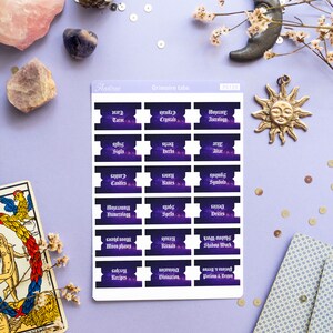 May include: A set of 18 purple and black planner stickers with a galaxy background. The stickers are labeled with various topics related to witchcraft, such as tarot, crystals, astrology, sigils, herbs, altar, candles, runes, symbols, numerology, spells, deities, moon phases, rituals, shadow work, recipes, divination, and potions & brews.