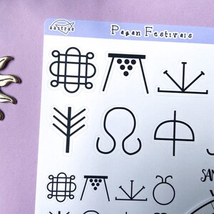 May include: A sheet of stickers with black and white illustrations of pagan festival symbols. The symbols include a circle with a knot, a table with grapes, a three-pronged fork, a tree, a sideways infinity symbol, an umbrella, a circle with a dot, and a sideways M. The text "Pagan Festivals" is at the top of the sheet.
