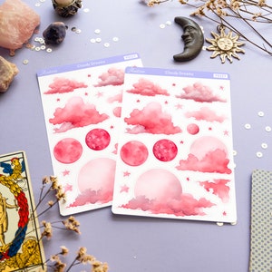 May include: Two sheets of pink and white stickers with a watercolor design of clouds, stars, and moons. The stickers are labeled "Cloudy Dreams" and have the product number "PS327".