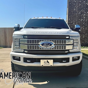 May include: White Ford Super Duty pickup truck with a chrome grille and headlights. The truck has a license plate that reads "The K9 Consultant Dog Training".