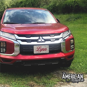 May include: A red Mitsubishi Outlander SUV with a custom license plate that reads "Lynn".