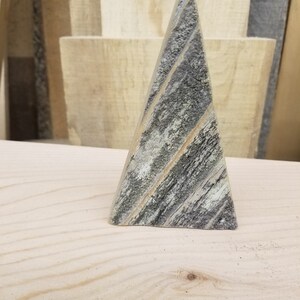 May include: A small wooden Christmas tree ornament with a gray and white weathered wood finish.