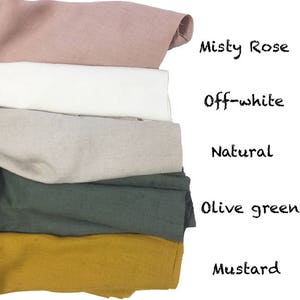 May include: A stack of folded fabric samples in various colors, including misty rose, off-white, natural, olive green, and mustard. The names of the colors are written in black script on the right side of the image.
