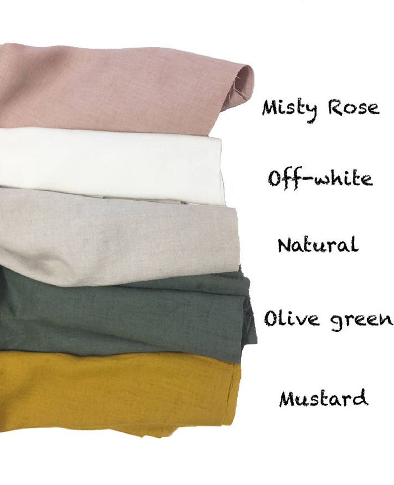 May include: A stack of folded fabric samples in various colors, including misty rose, off-white, natural, olive green, and mustard. The names of the colors are written in black script on the right side of the image.