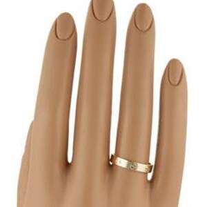 May include: Close-up of a yellow gold wedding band featuring a thin band with small, evenly spaced diamonds. The band is simple and elegant, showcasing a classic design.  The diamonds are brilliant and add subtle sparkle to the piece. This is a luxury jewelry item, perfect for engagement or wedding celebrations.