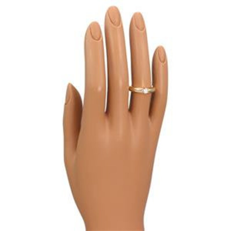 May include: A gold band ring with a single round diamond set in the center. The ring is on a white background.