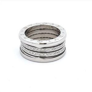 May include: A silver ring with four bands, two of which are set with diamonds. The ring is engraved with the brand name "BVLGARI".